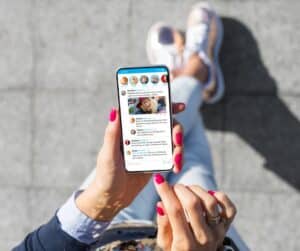 Woman walking and holding a mobile phone looking at her social media as businesses try to make her one of many website visitors through social media marketing